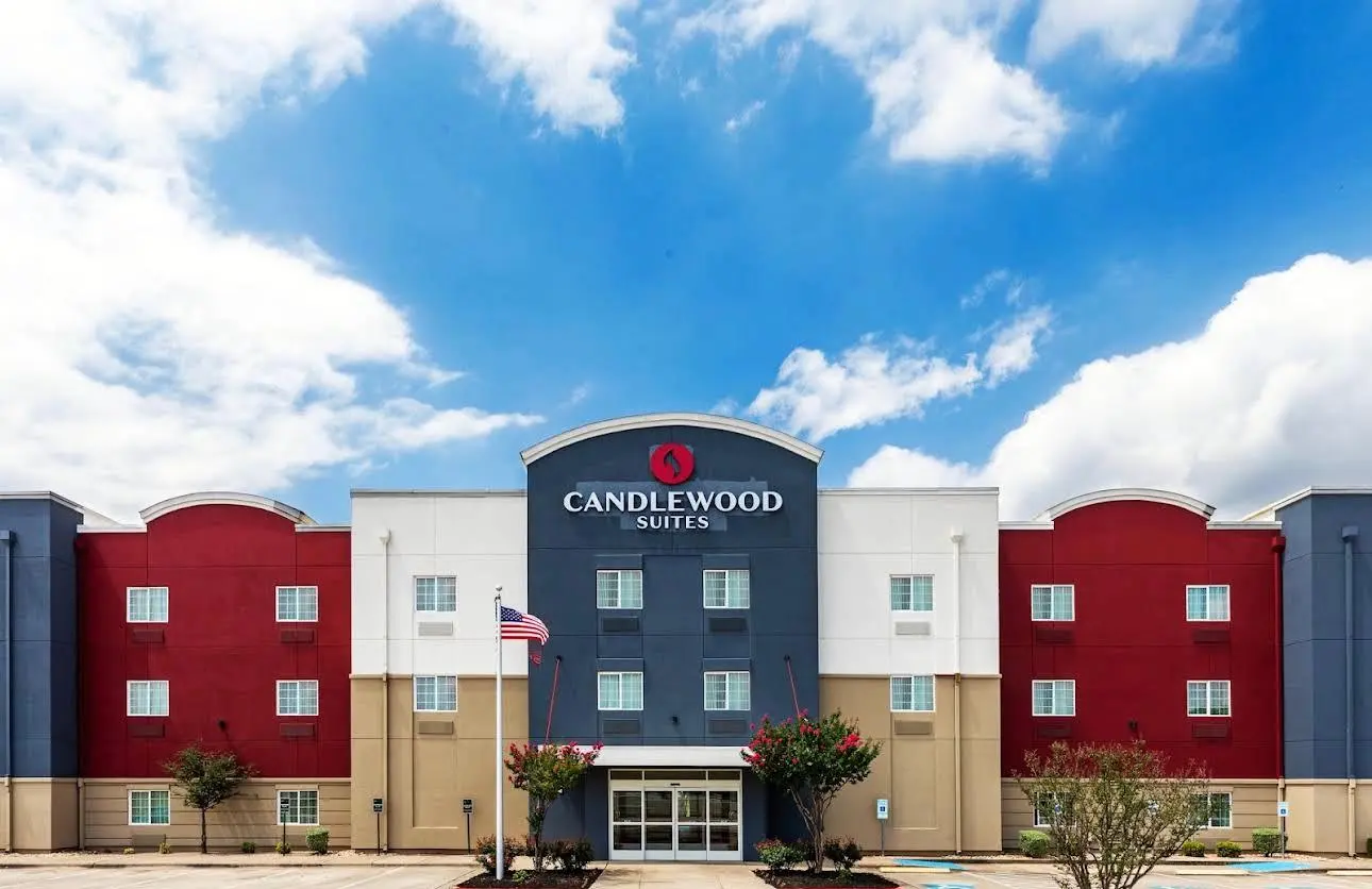 A Candlewood Suites in red, white and blue under a bright cloudy sky
