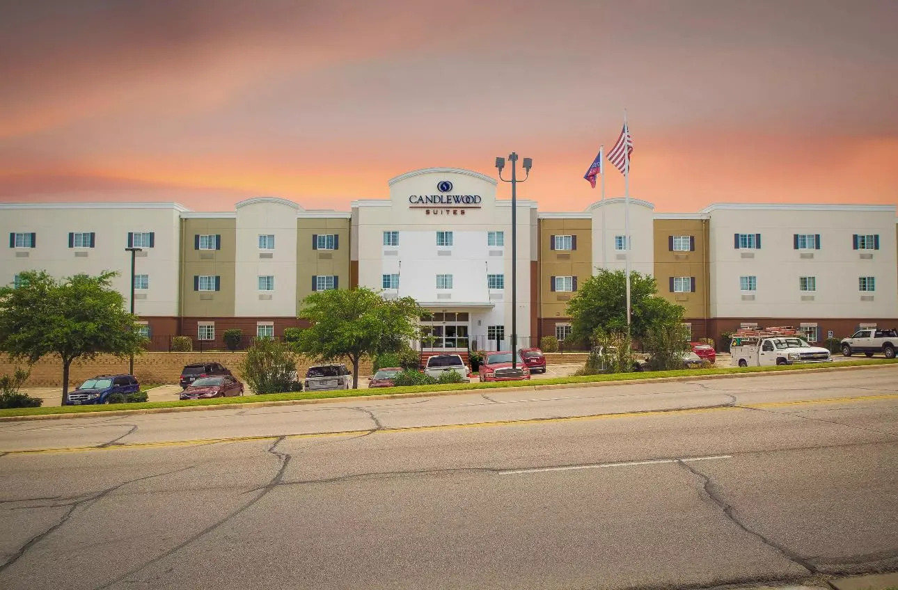 A Candlewood Suites across the road at sunset, flags flying over the entrance