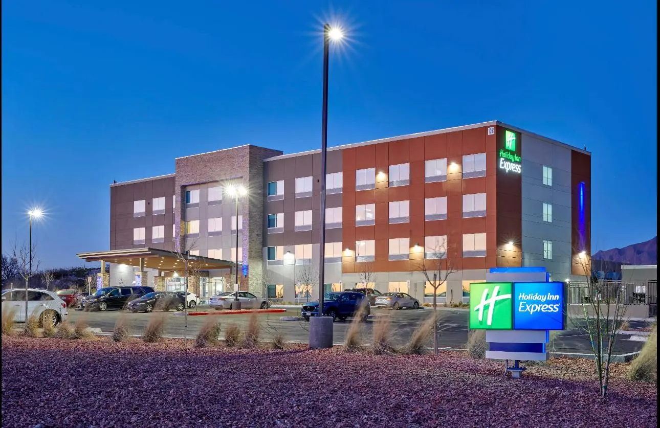 A Holiday Inn Express at dusk under a deep blue sky, its sign lit, mountains behind