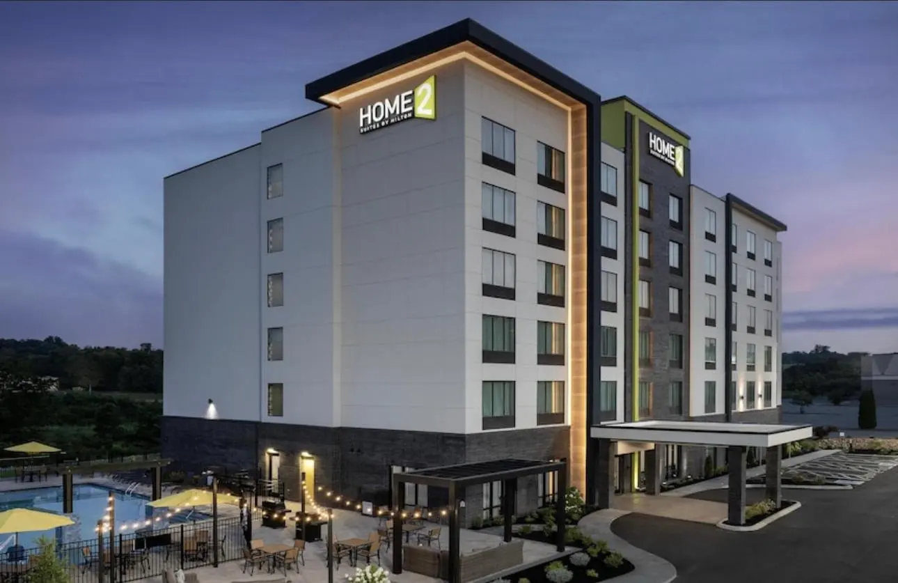 A Home2 Suites by Hilton at dusk, seen across its pool terrace and porte-cochère