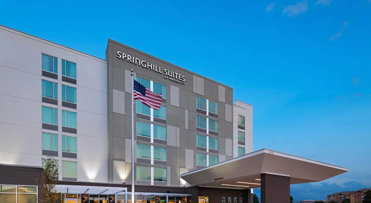 A SpringHill Suites by Marriott at dusk, the flag flying before its entrance canopy